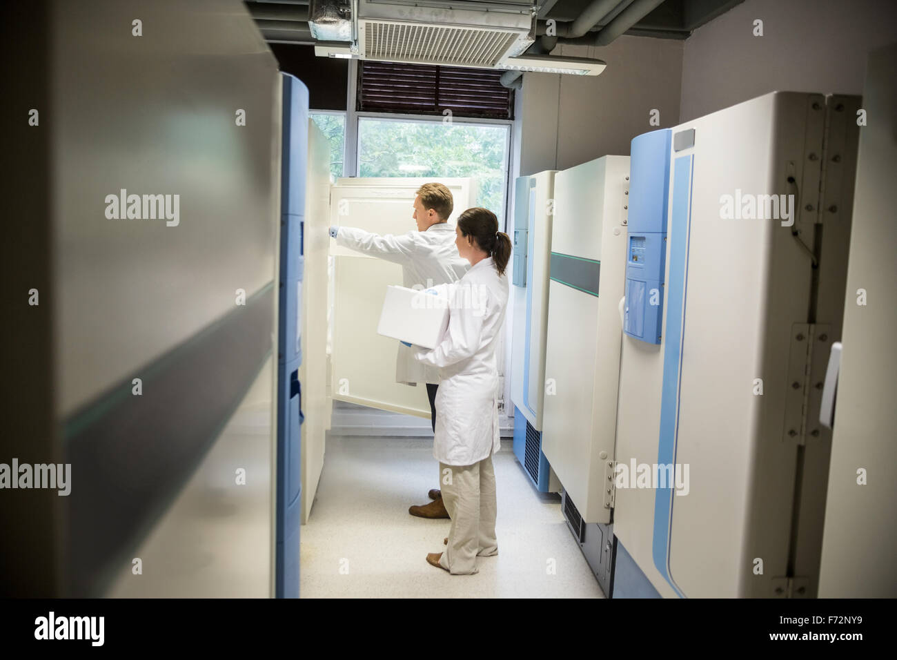 Two scientists using large fridge unit Stock Photo