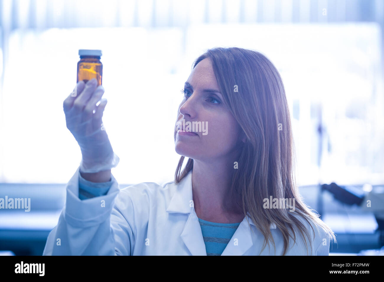 Scientist looking at beaker of chemical Stock Photo