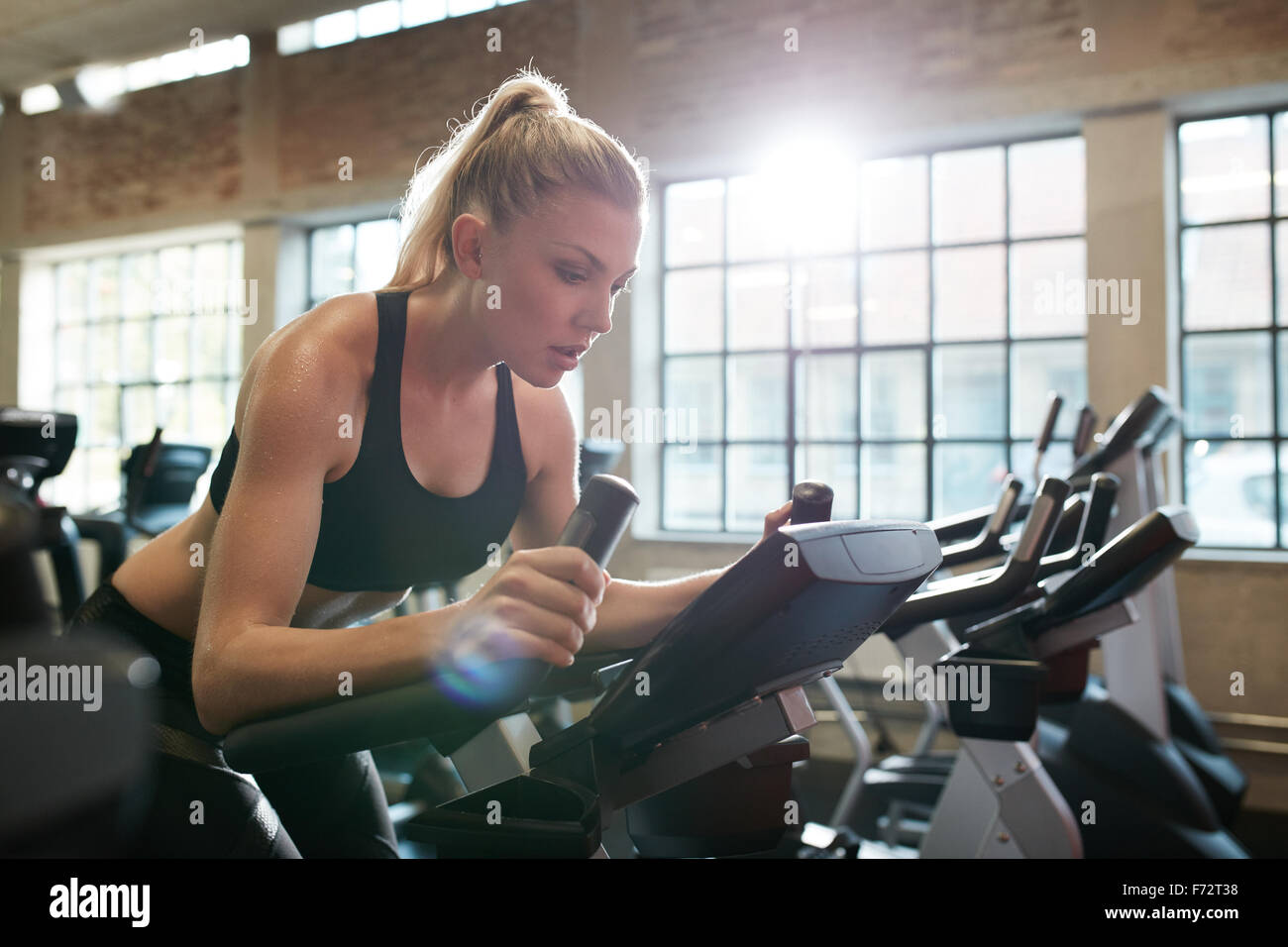 Fit woman working out on exercise bike at the gym. Indoor shot of a female doing fitness training on spinning bicycle at health Stock Photo