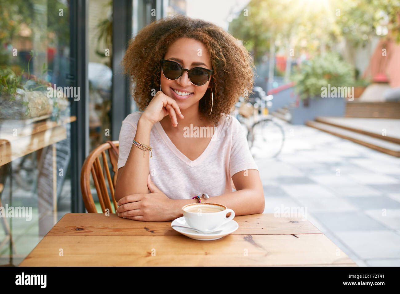 Portrait of attractive young woman sitting at outdoor coffee shop with