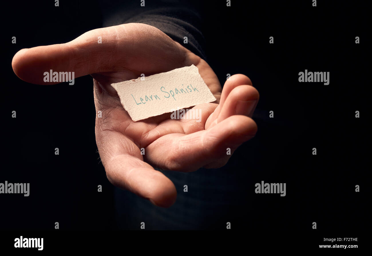 A man holding a card with a hand written message on it, Learn Spanish. Stock Photo