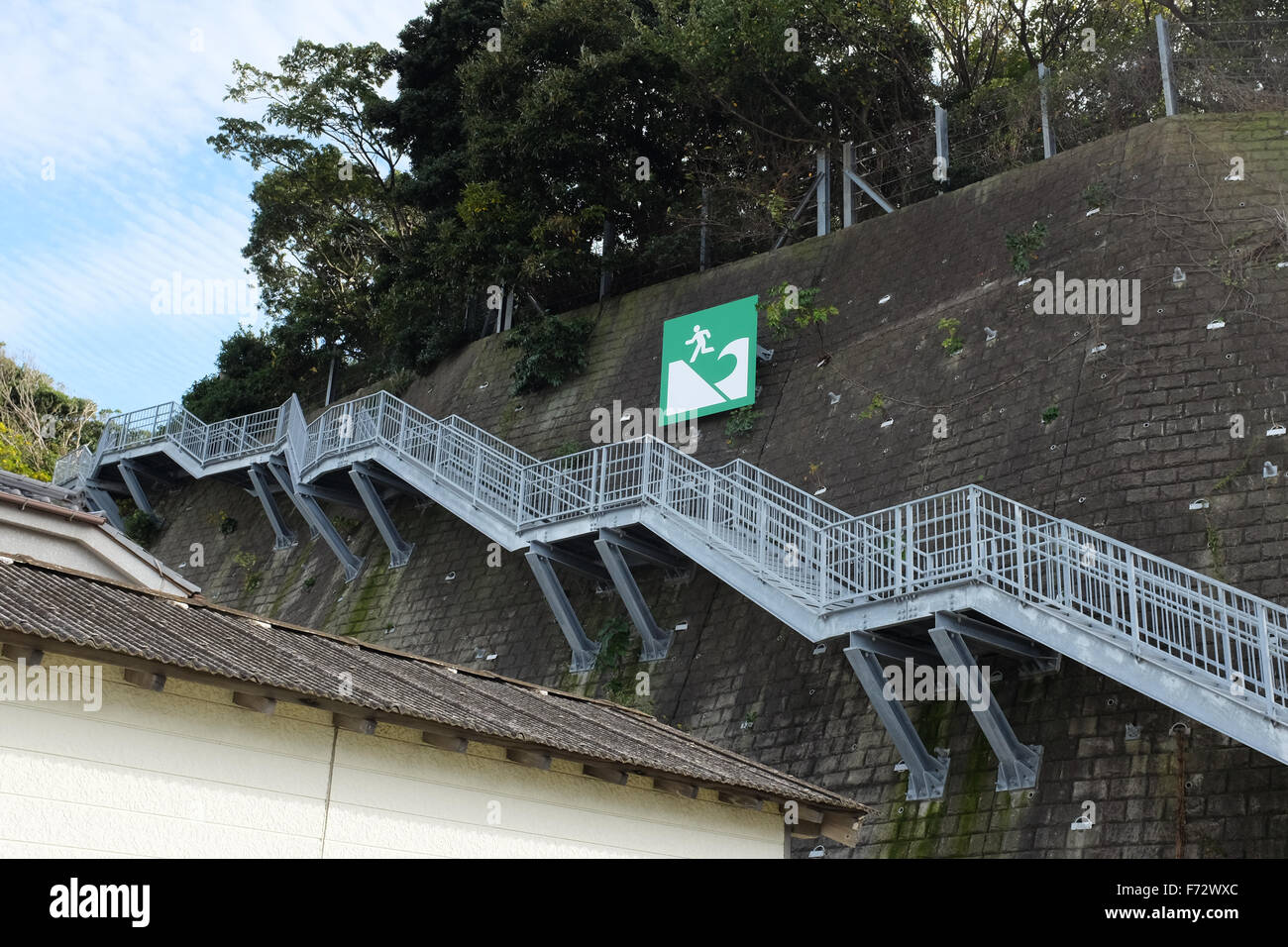 A sign in Japan directing people up steps to a safe zone in the event of a tsunami hitting land. Stock Photo