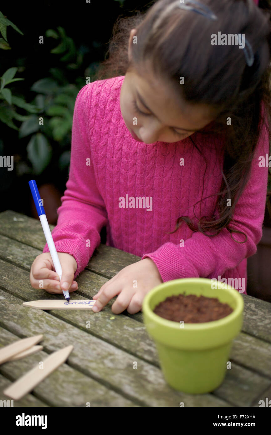 Young girl (seven year old) writing out a plant label for crocus Stock Photo