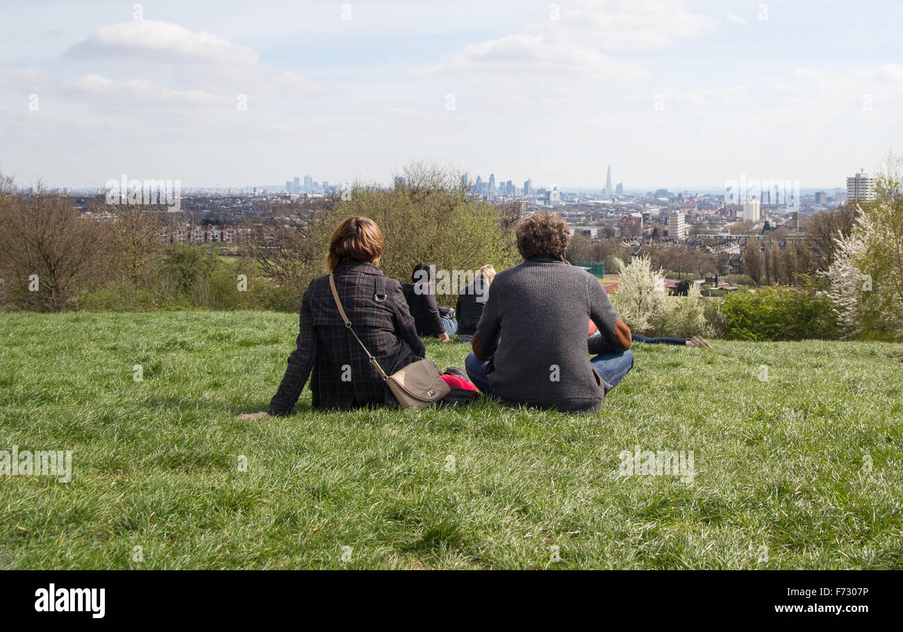 A couple Relaxing and enjoying the view from Parliament hill in Hampstead Heath of the London Skyline Stock Photo