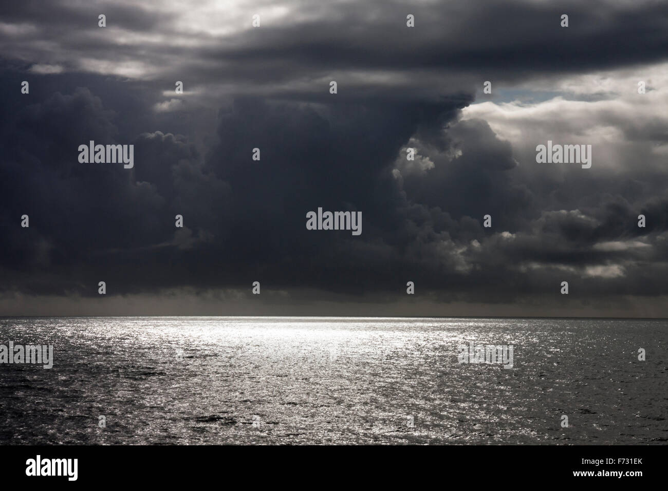 Light shines through storm clouds over the sea approaching the south coast at Hastings, East Sussex, England, UK Stock Photo
