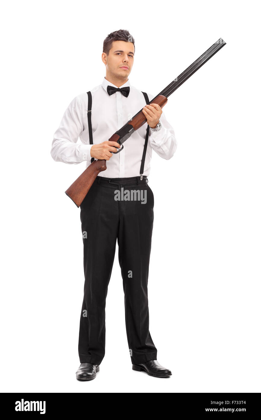 Full length portrait of an armed young man holding a shotgun rifle and looking at the camera isolated on white background Stock Photo