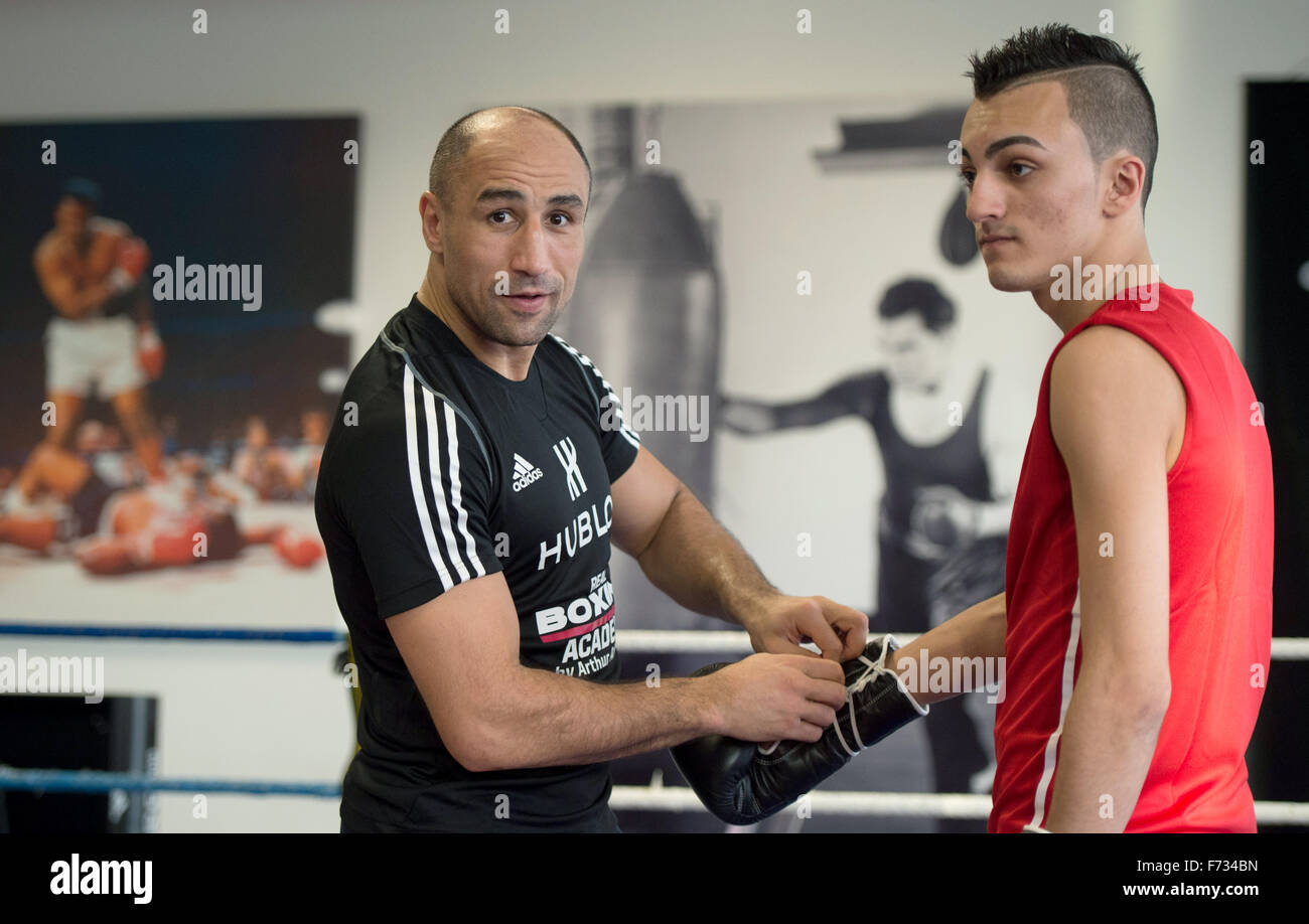 Boxing world champion Arthur Abraham helps a young refugee from Iraq put on boxing gloves prior to a training session at the Max Schmeling Gymnasium in Berlin, Germany, 24 November 2015. The event featuring unaccompanied refugees was organised by Team Sauerland, sporting goods manufacturer Adidas, the German Confederation of   Skilled Crafts and German political party CDU. Photo: SOEREN STACHE/dpa Stock Photo