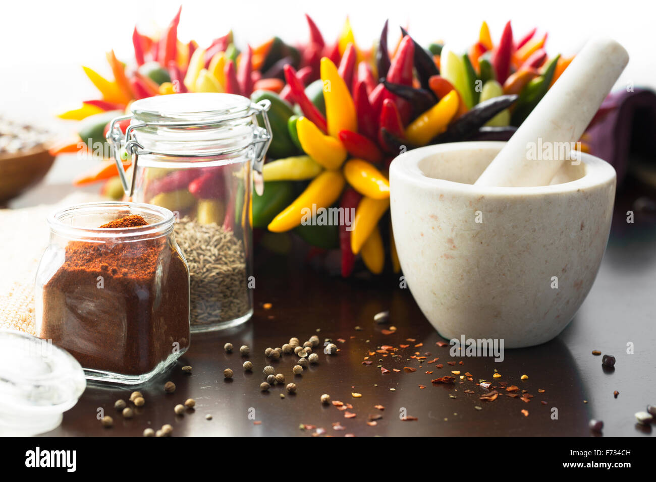 Fresh colorful chili peppers and ground chili pepper with mortar and pestle. Stock Photo