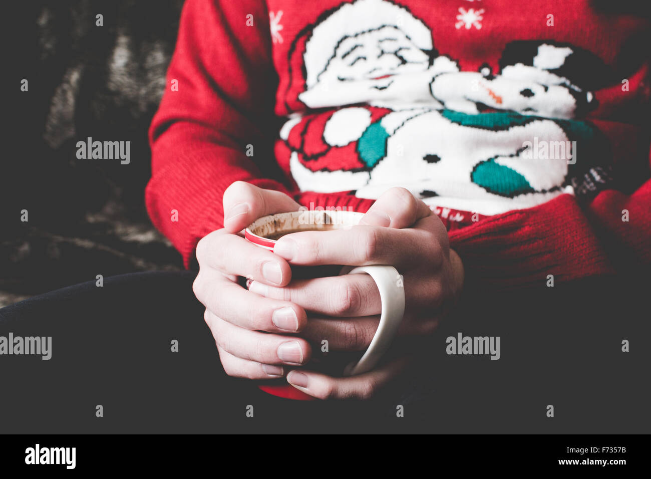 Man wearing a Christmas jumper and holding a hot chocolate Stock Photo