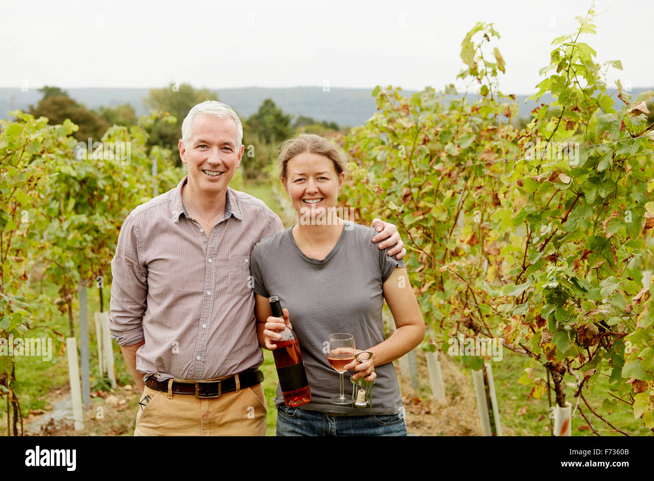 A couple, vineyard founder and her partner standing among the rows of vines. Stock Photo
