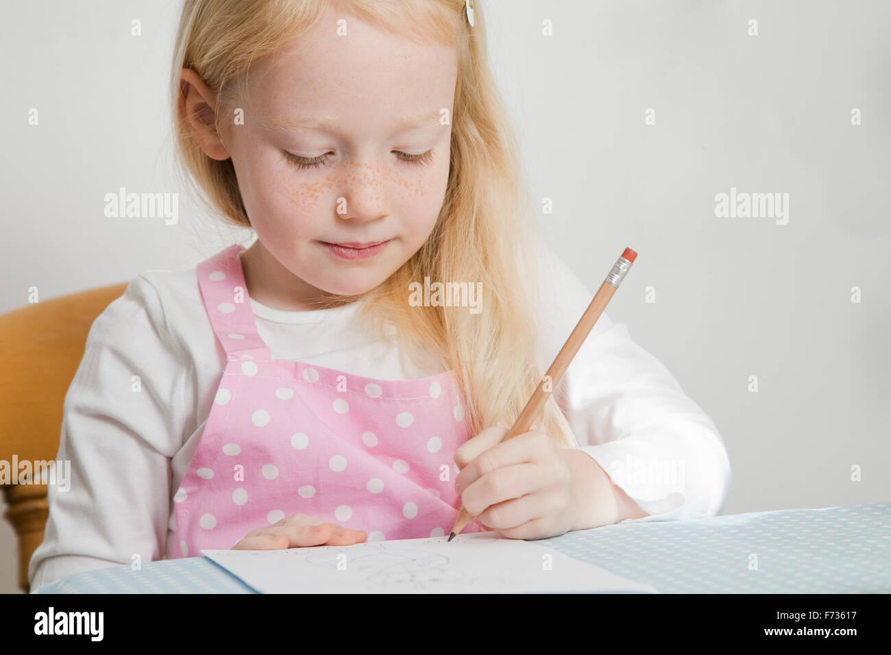 A girl sitting at a table drawing. Stock Photo