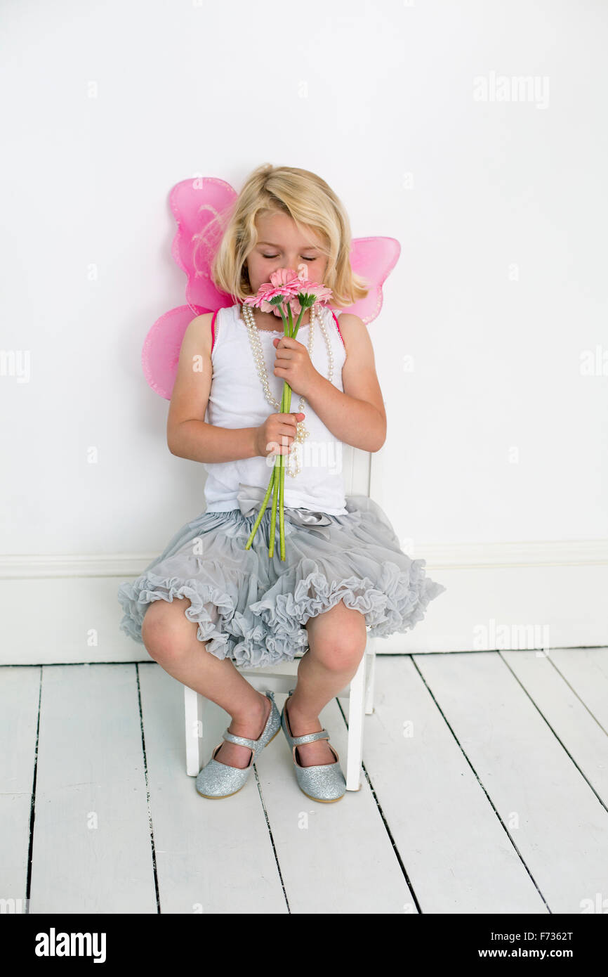 Young girl posing for a picture in a photographers studio, holding a bunch of flowers. Stock Photo