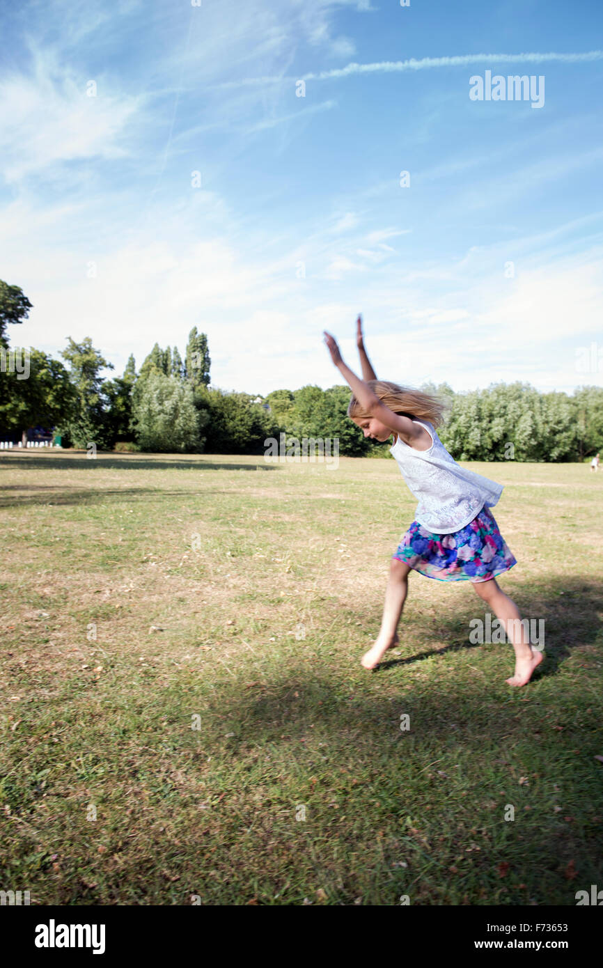 Young girl playing in a park, preparing to do a handstand. Stock Photo