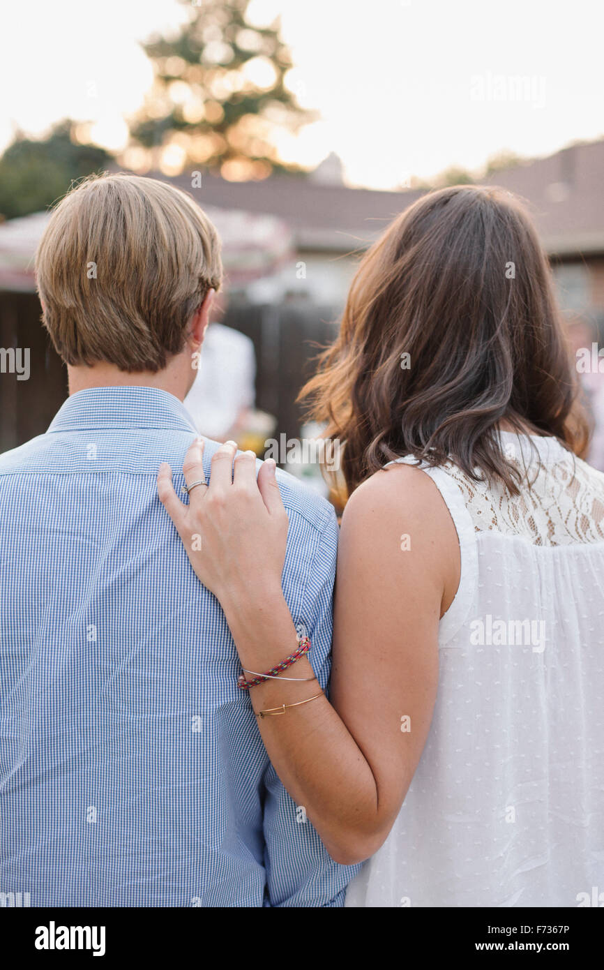 Rear view of a couple standing side by side in a garden, woman touching man's shoulder. Stock Photo