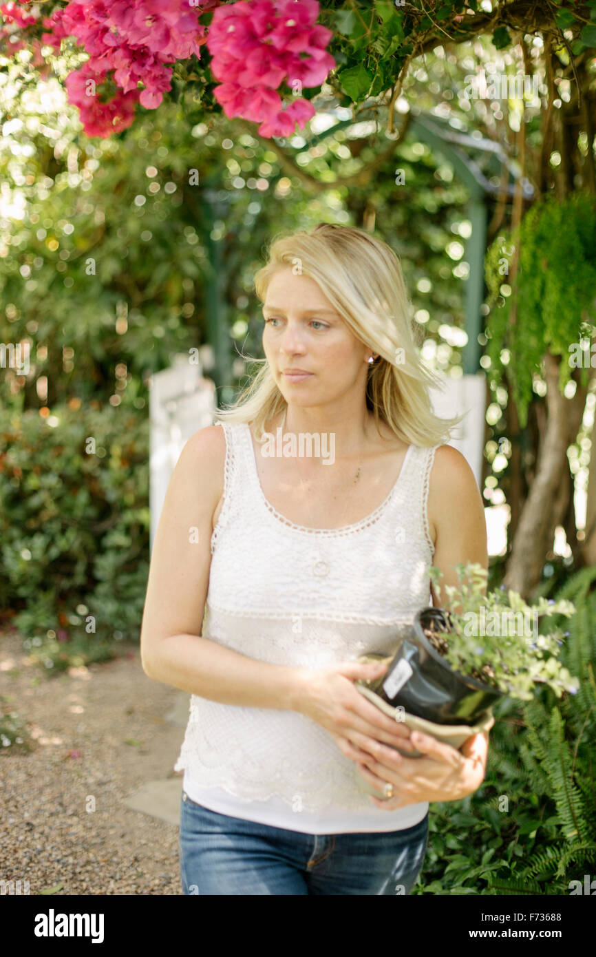 Blond woman in a garden, holding a plant pot Stock Photo - Alamy