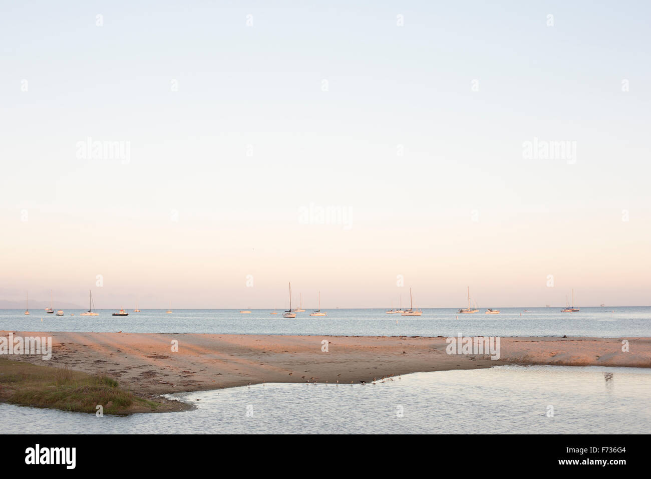 Sandy beach and ocean, sailing boats in the distance. Stock Photo