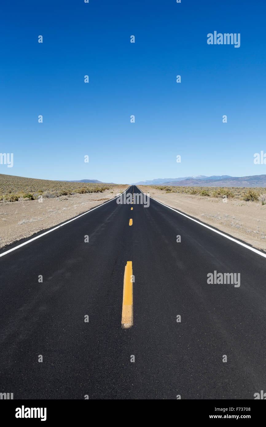 A black top road with a central line reaching into the distance, the road ahead. Stock Photo