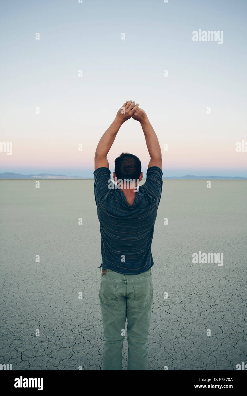 Man stretching with arms above head, facing the sunrise over expansive desert, Black Rock Desert, Nevada Stock Photo