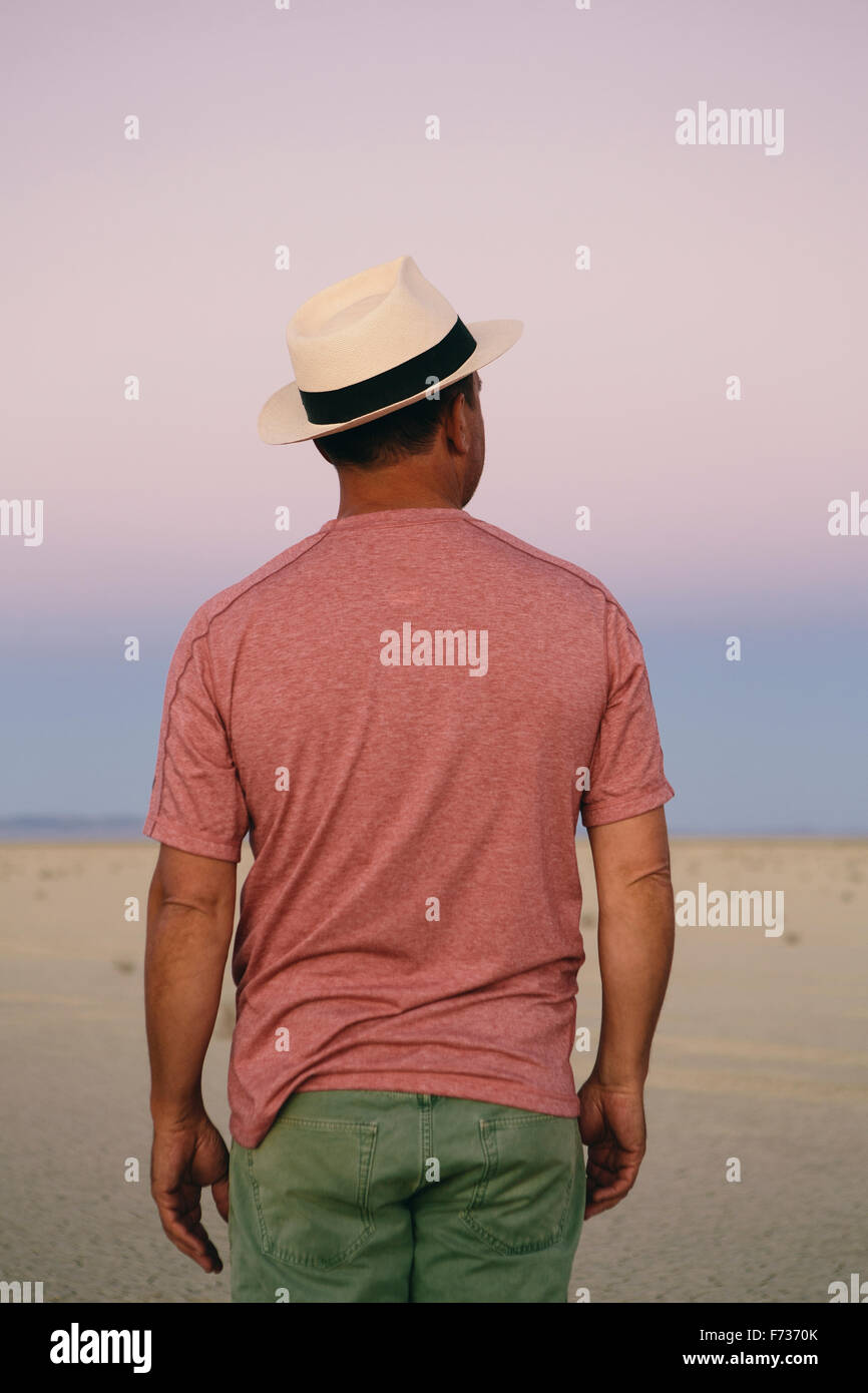 A man in a straw hat pausing to take in view of the landscape of the playa at dawn in the desert. Stock Photo
