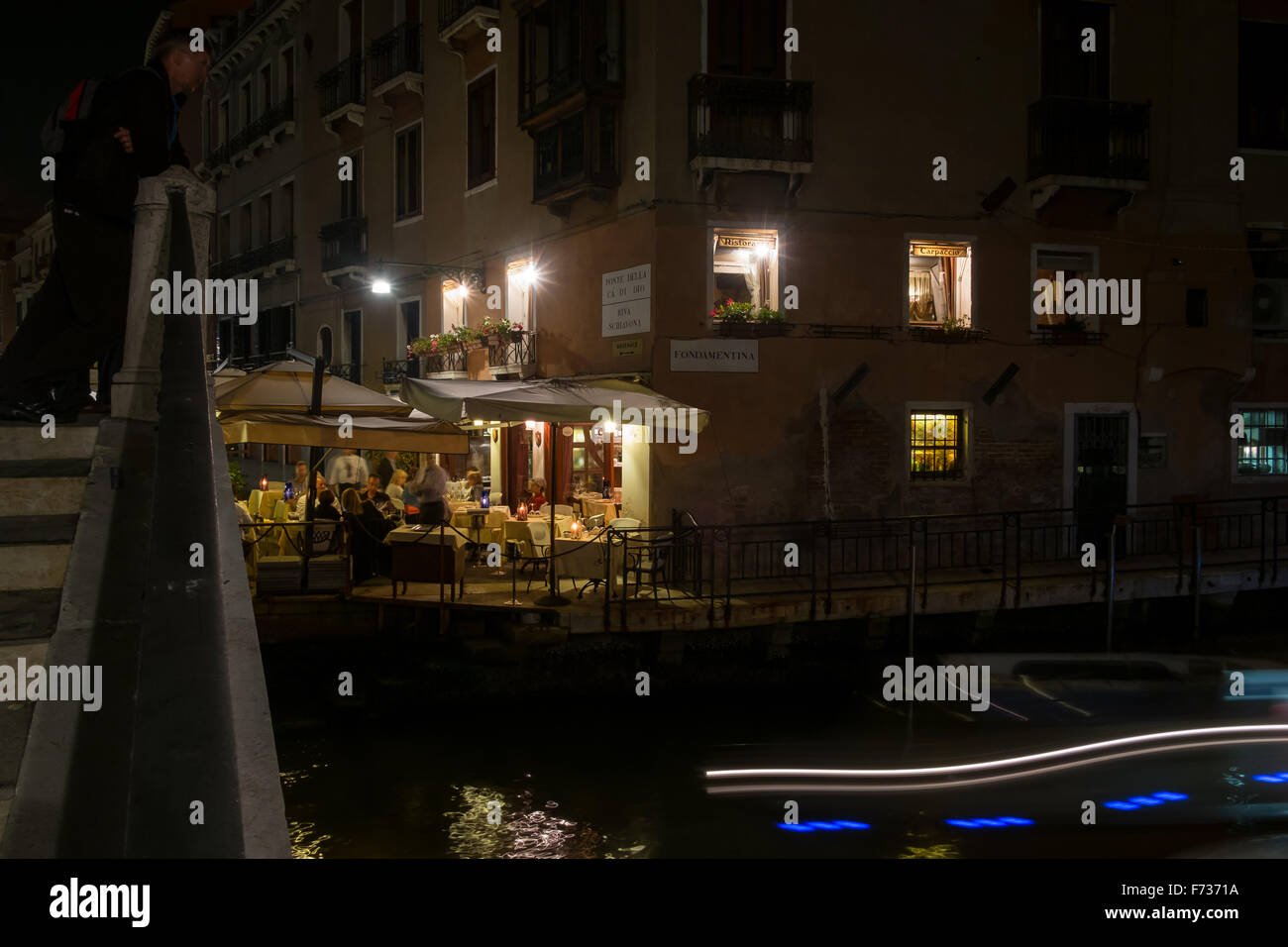 Busy restaurant at night alongside canal in Venice, Italy. Stock Photo