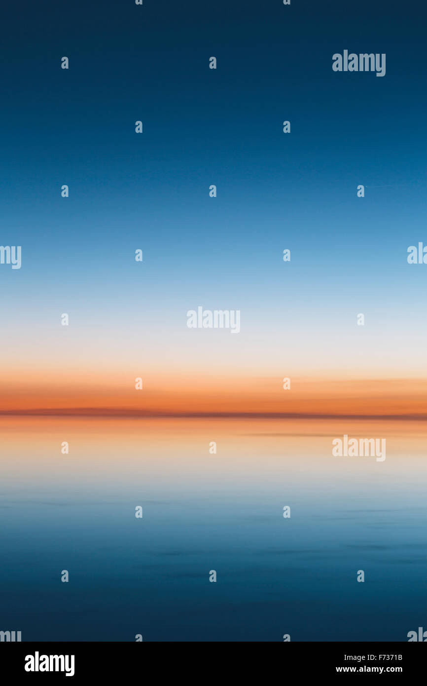 The view to the clear line of the horizon where land meets sky, across the flooded surface of Bonneville Salt Flats. Dawn light, Stock Photo