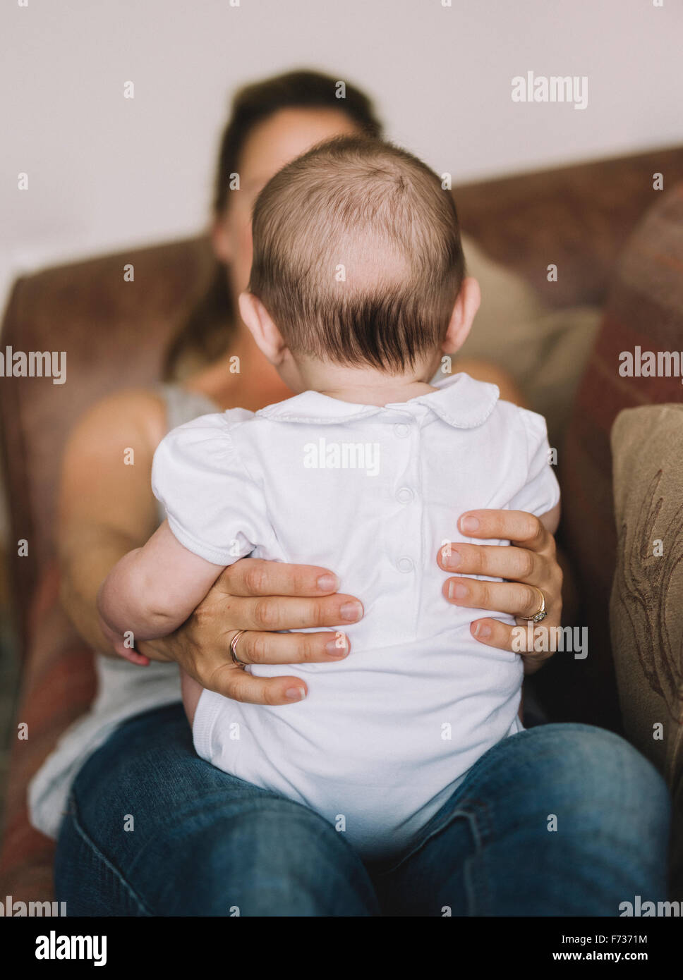 A woman holding a baby girl on her knee. Stock Photo