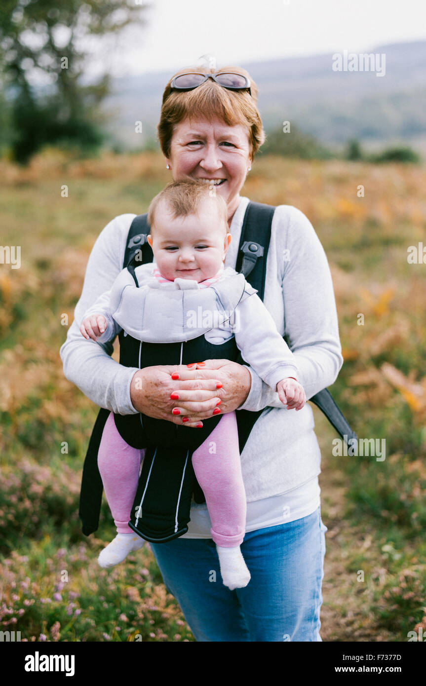 A woman carrying a baby in a baby carrier, on an autumn walk. Stock Photo