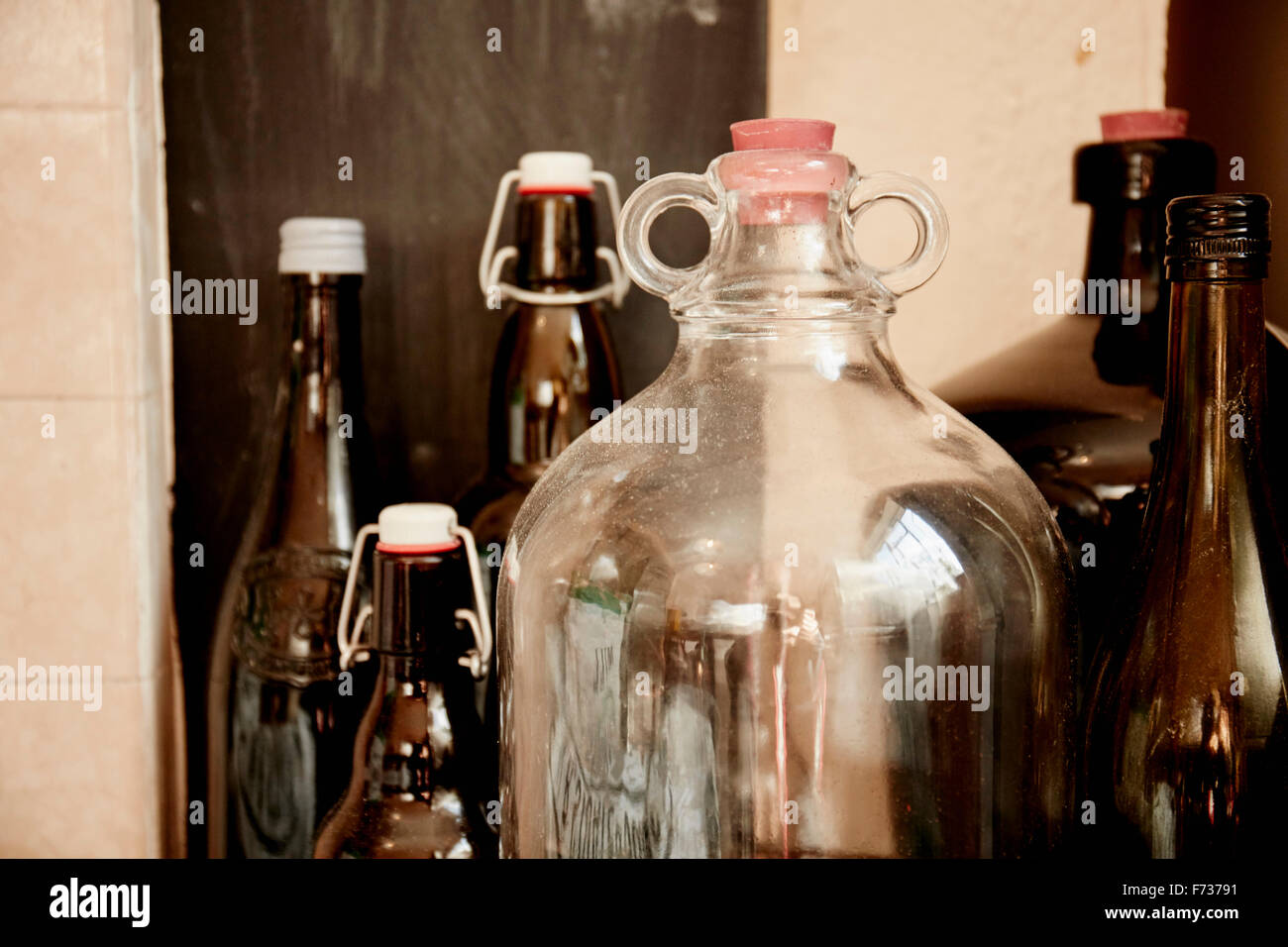 A shelf of bottles and jars, one large double handled jar with a