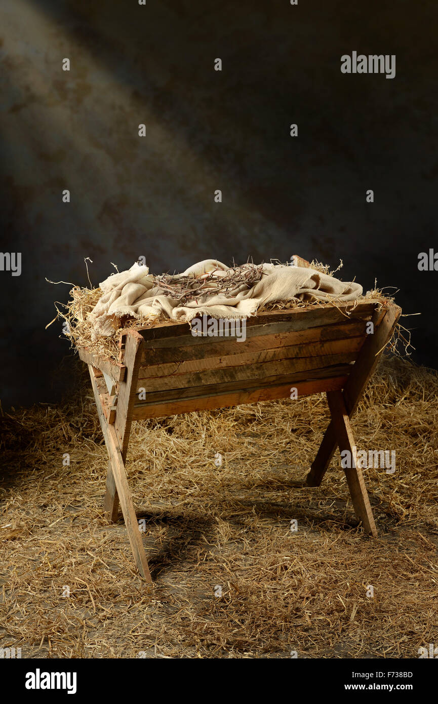 Manger with crown of thorns in barn with light coming from above Stock Photo