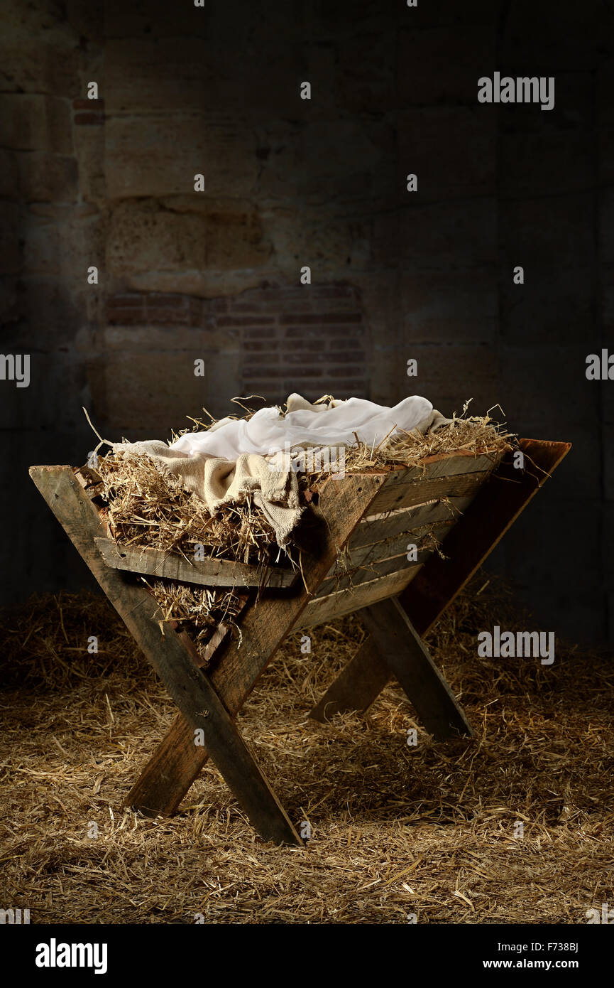 Manger filled with hay in stable with baby soft cloths on top Stock Photo