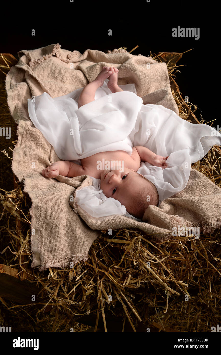 Jesus resting on a manger over dark background Stock Photo