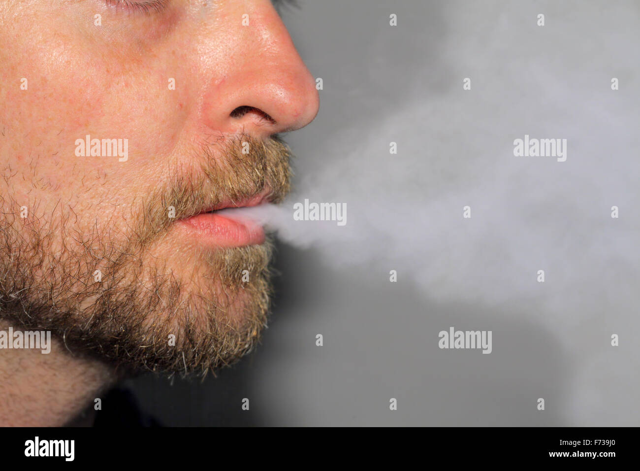 Bearded man exhaling vapor from an e-cigarette. Stock Photo