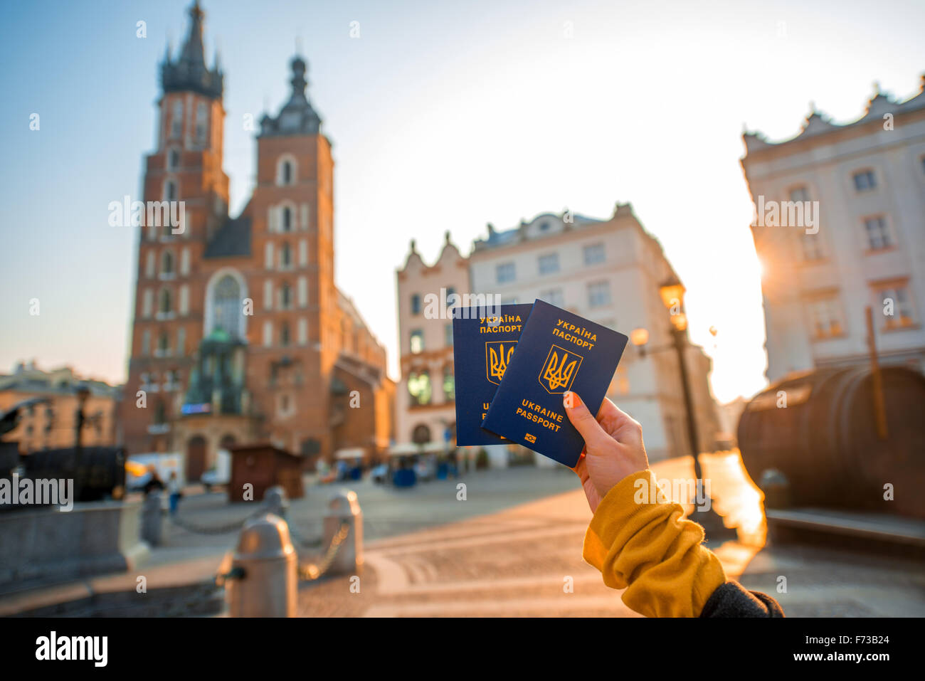Female hands holding Ukrainian abroad passports on the Krakow city center background. Traveling to Europe from Post-Soviet count Stock Photo