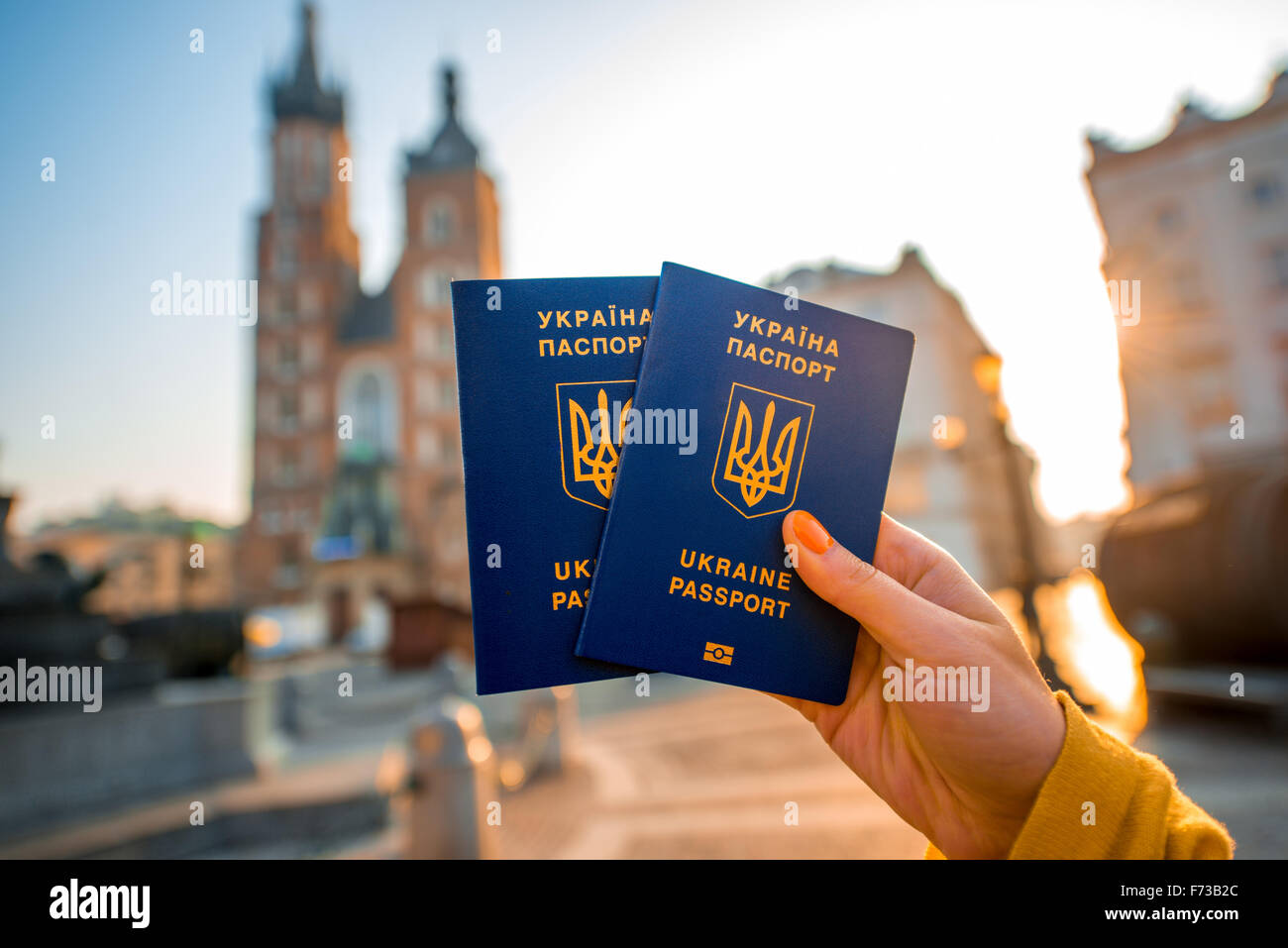 Female hands holding Ukrainian abroad passports on the Krakow city center background. Traveling to Europe from Post-Soviet count Stock Photo
