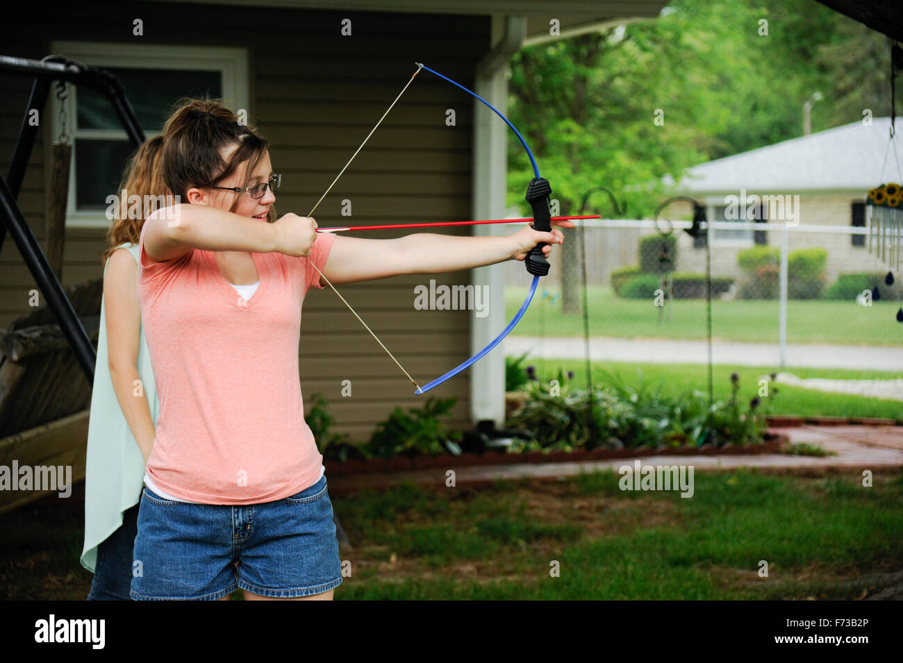 Pre-teen girl with bow and arrow in back yard Stock Photo