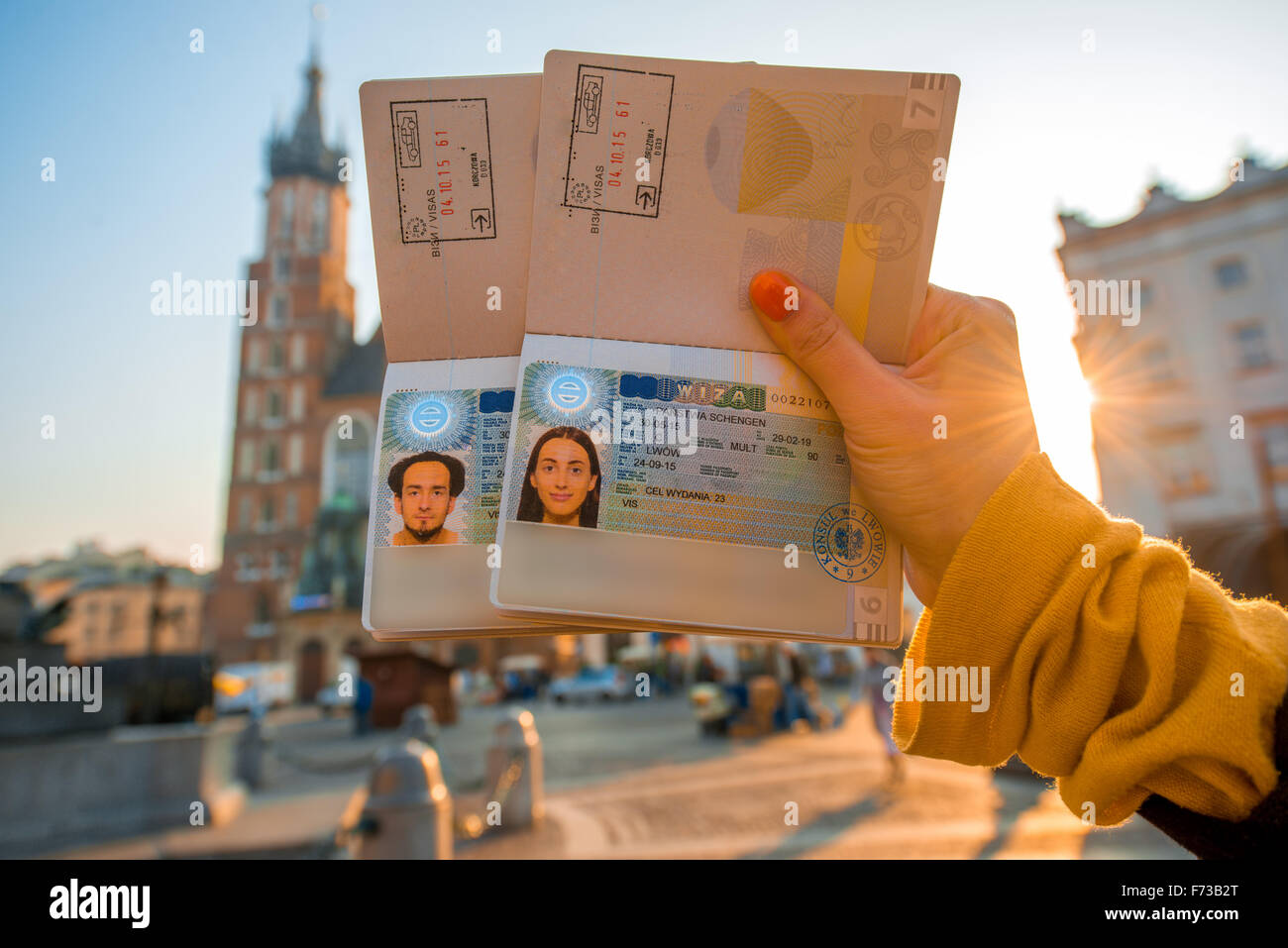 Female hands holding Ukrainian passports with Shengen visas on the Krakow city center background. Traveling to Europe from Post- Stock Photo