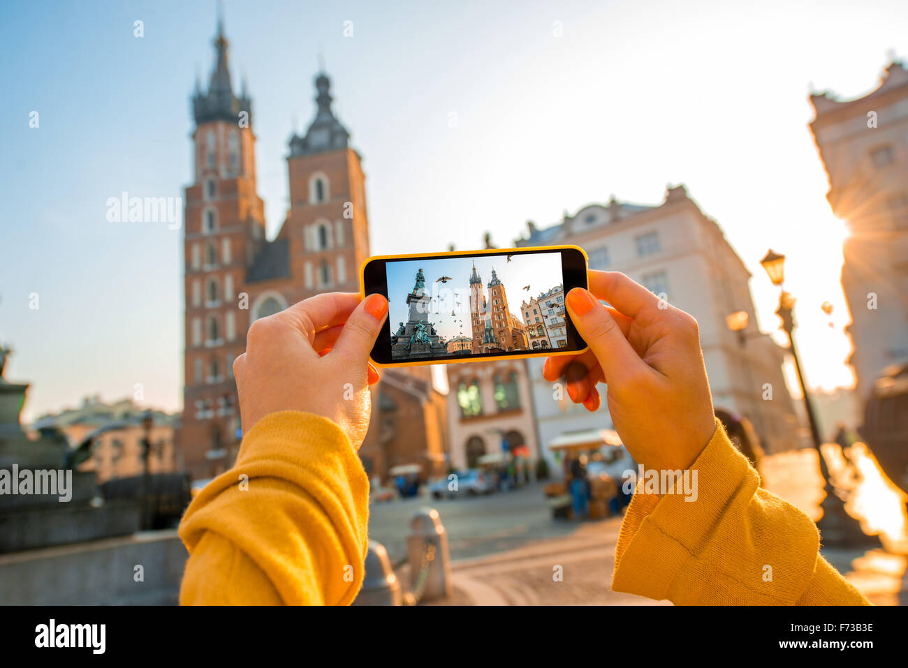 Female hands photographing St. Marys Basilica with mobile phone on the sunrise in Krakow Stock Photo