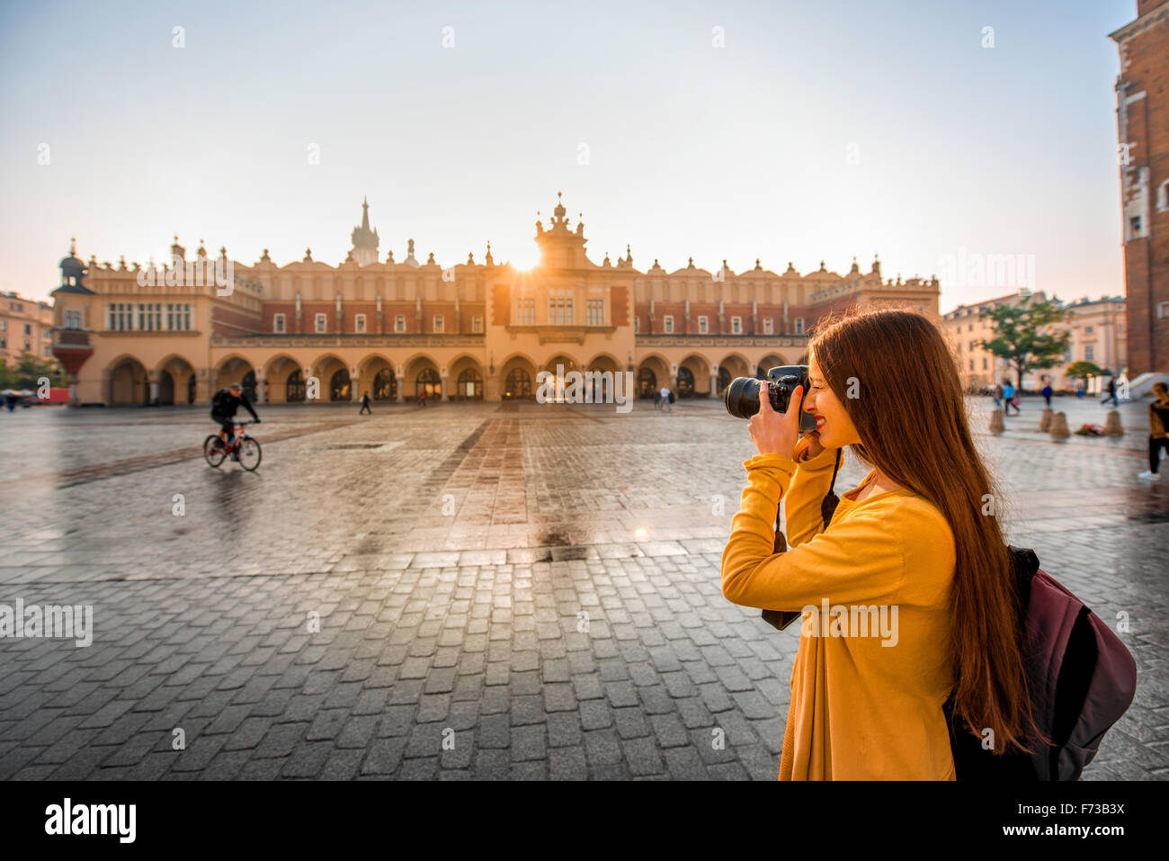 Young female tourist with camera and backpack photographing Cloth Hall in the old city center of Krakow Stock Photo