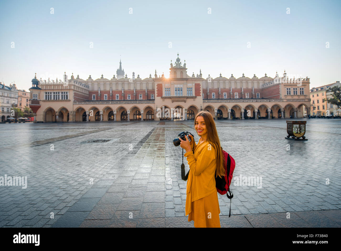Young female tourist with camera and backpack photographing Cloth Hall in the old city center of Krakow Stock Photo