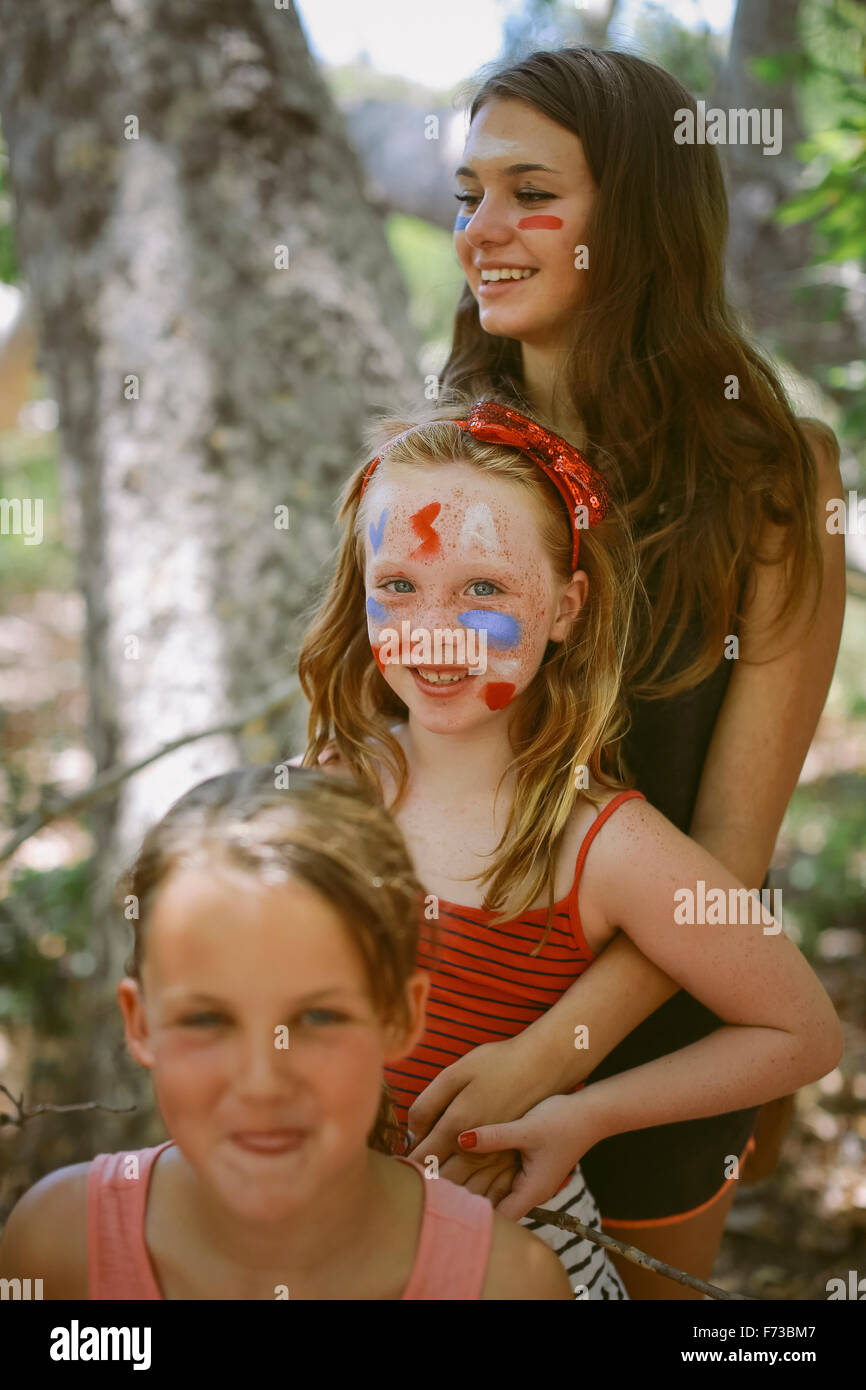 There young girls stand in a line with their face painted in red, white and blue colour. Stock Photo