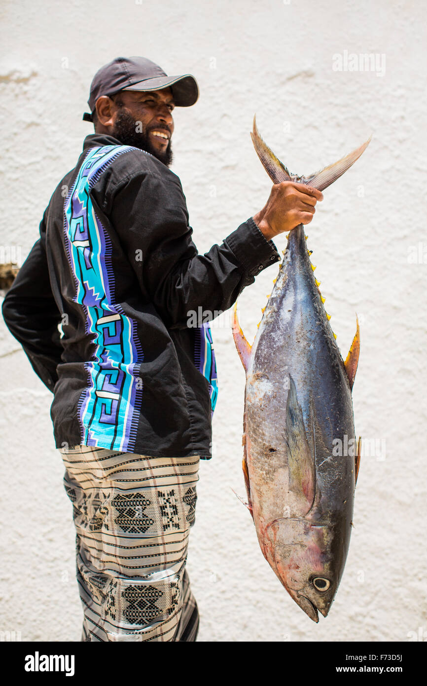 LAMU, KENYA, AFRICA. A man in traditional dress holds a lage tuna by