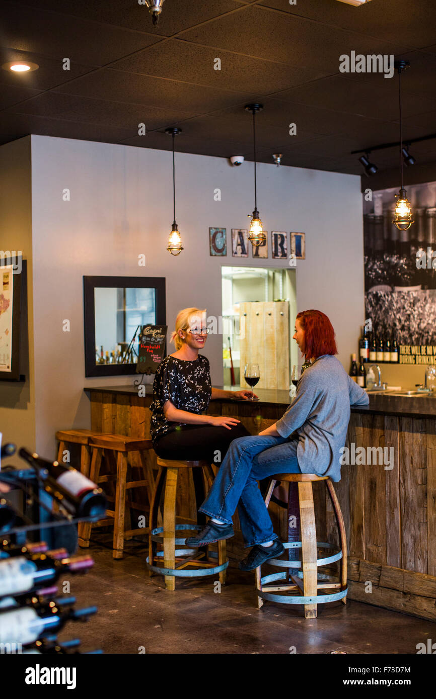 Two women sit at the bar of a wine tasting room and enjoys unique wines from all over the Northwest. Stock Photo