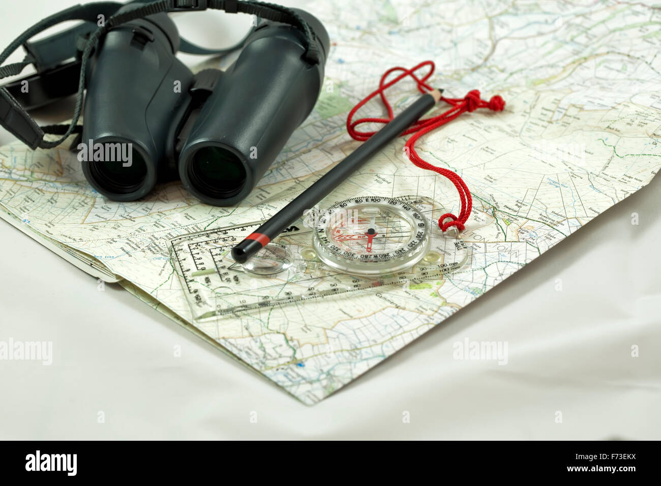 Image of a pair of binoculars sitting on a ordnance survey map with a compass and a pencil Stock Photo
