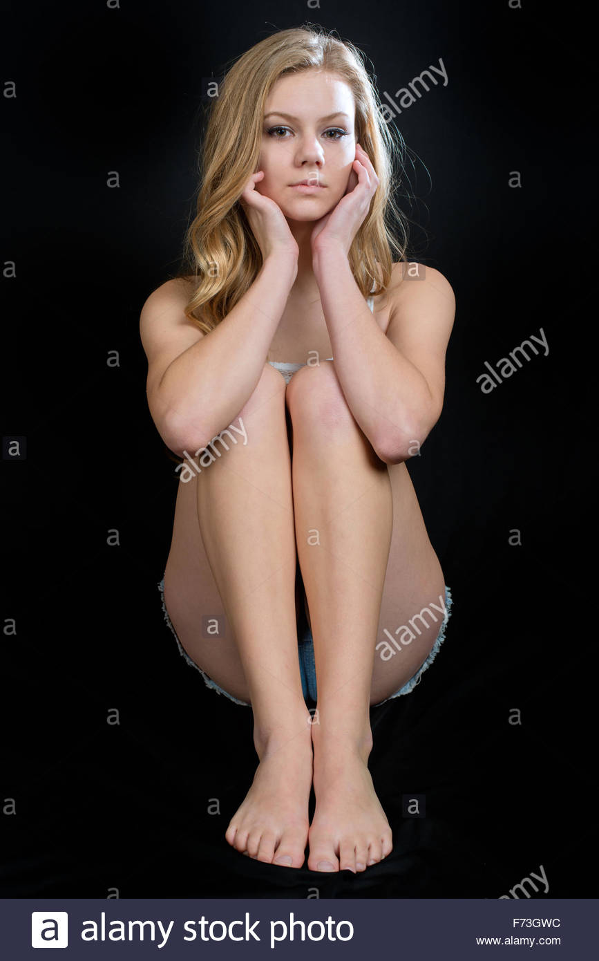 Teen girl in a white top sitting looking face on at the camera Stock Photo  - Alamy