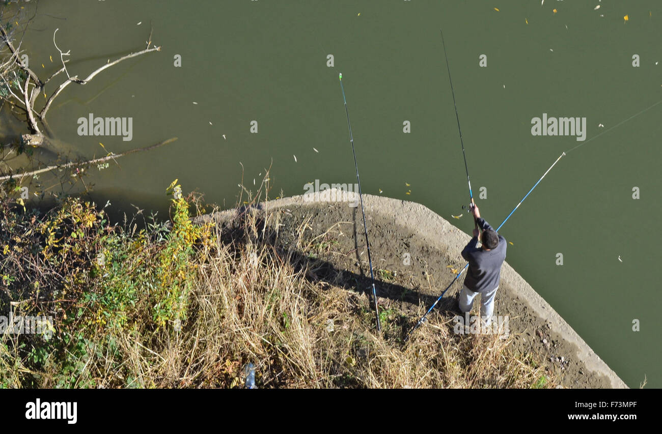 Fisherman at the foot of the bridge catching fish. Stock Photo