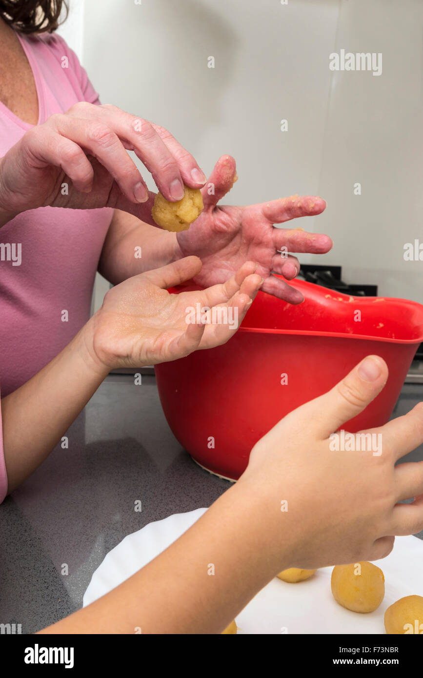 Mother and daughter kneading marzipan for make panellets  in the kitchen. Stock Photo