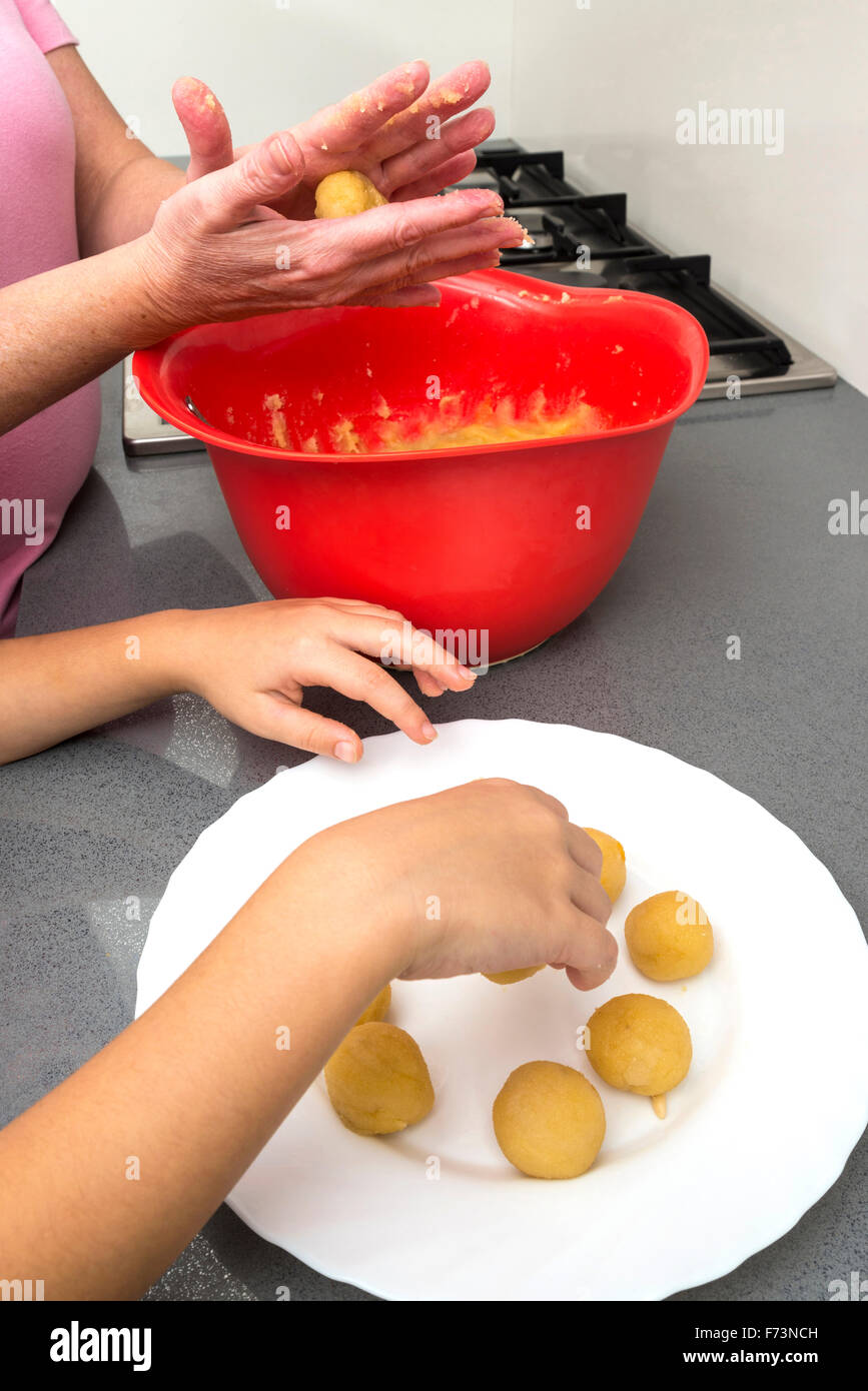 Mother and daughter kneading marzipan for make panellets  in the kitchen. Stock Photo