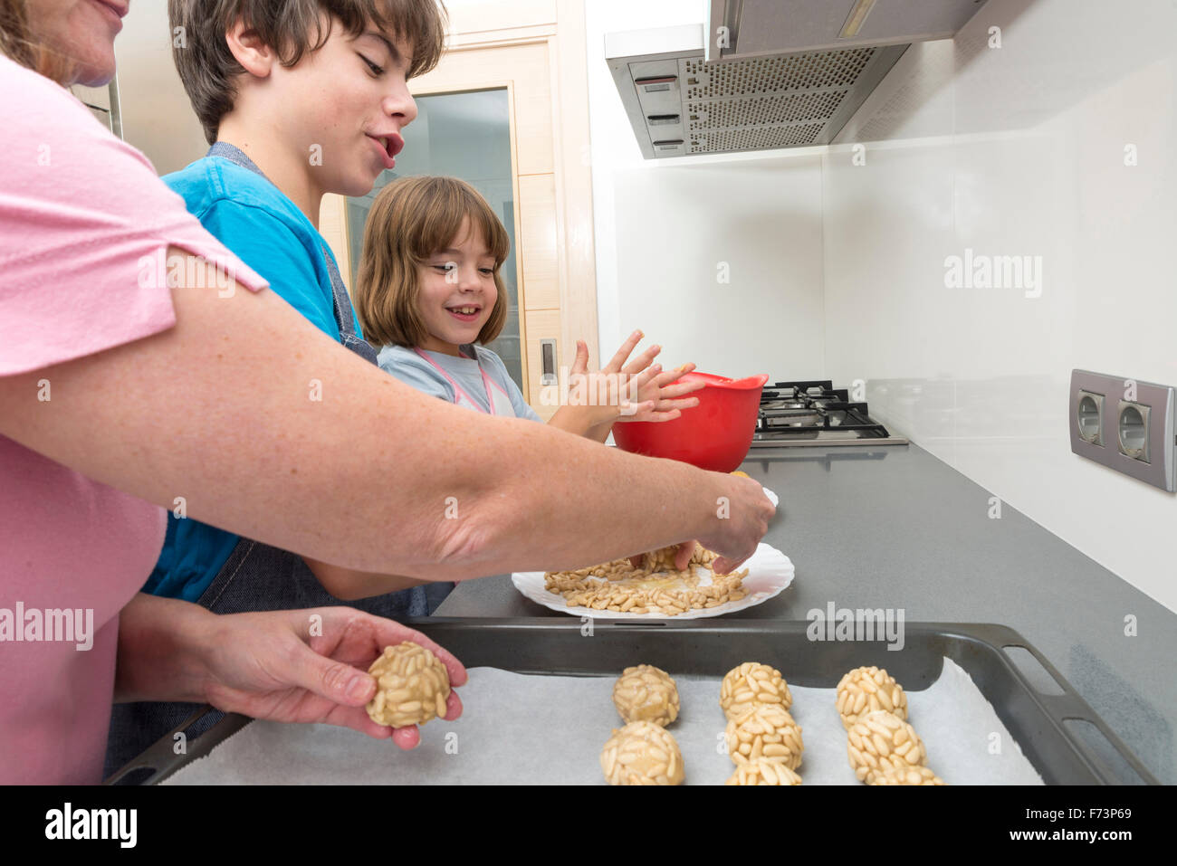 Family kneading marzipan for make panellets in the kitchen. Stock Photo