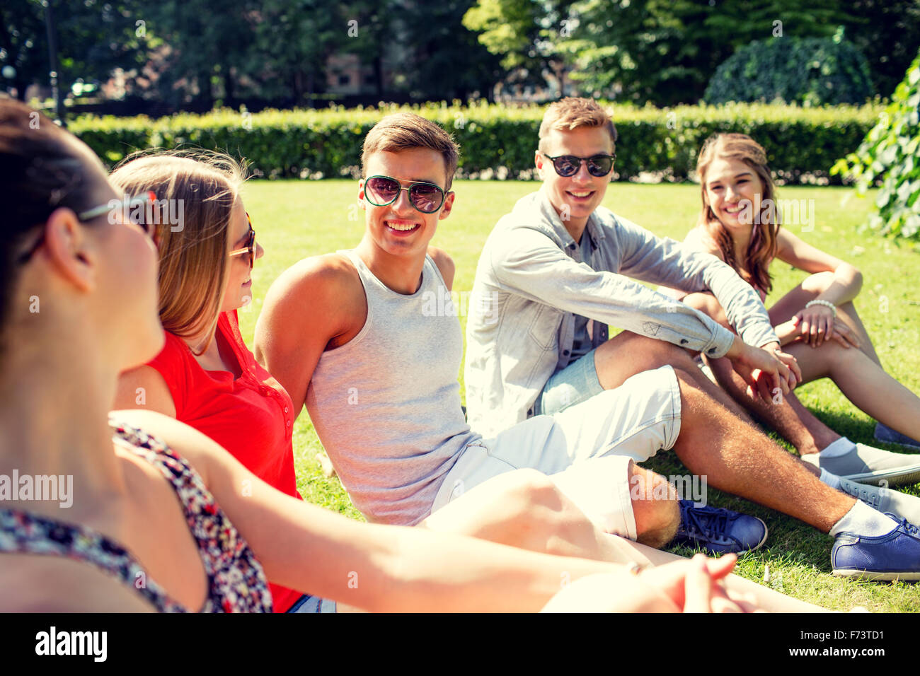 group of smiling friends outdoors sitting in park Stock Photo - Alamy
