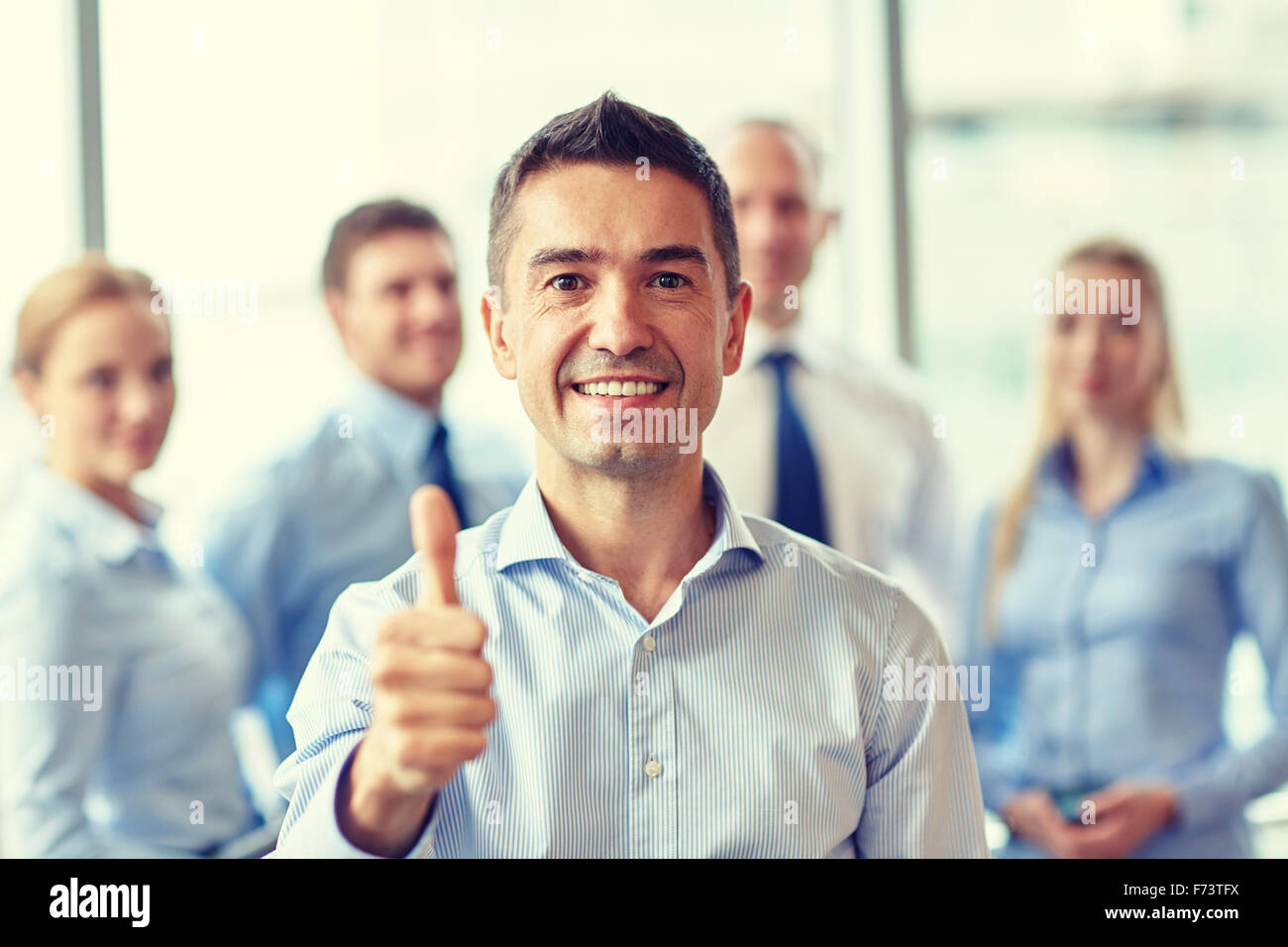 smiling business team showing thumbs up in office Stock Photo - Alamy